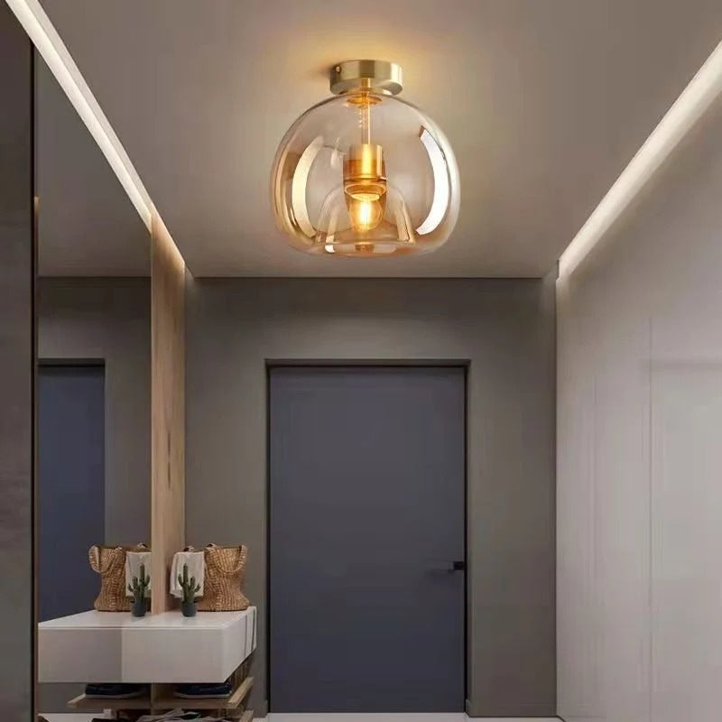 Nordic amber glass globe flush ceiling light with gold fittings glowing in a hallway