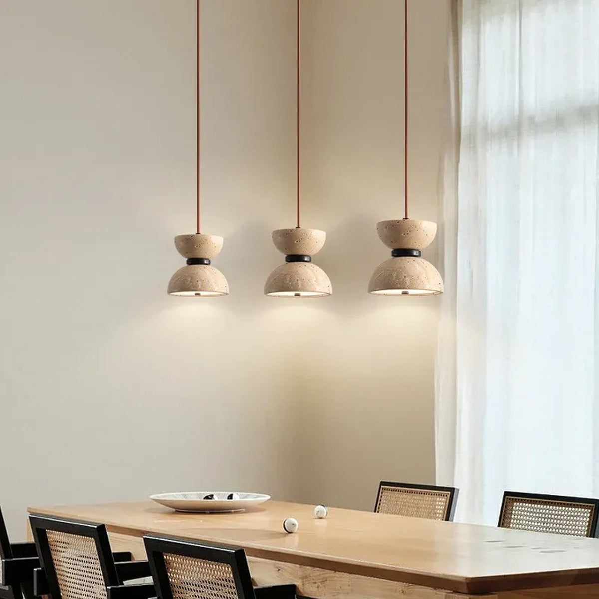 Three Sable travertine hourglass pendant lights over a dining table