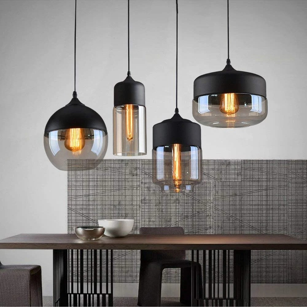 Arlo black and amber glass pendant lights in globe, slim cylinder and wide dome shapes above a dining table