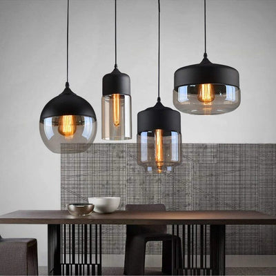 Arlo black and amber glass pendant lights in globe, slim cylinder and wide dome shapes above a dining table