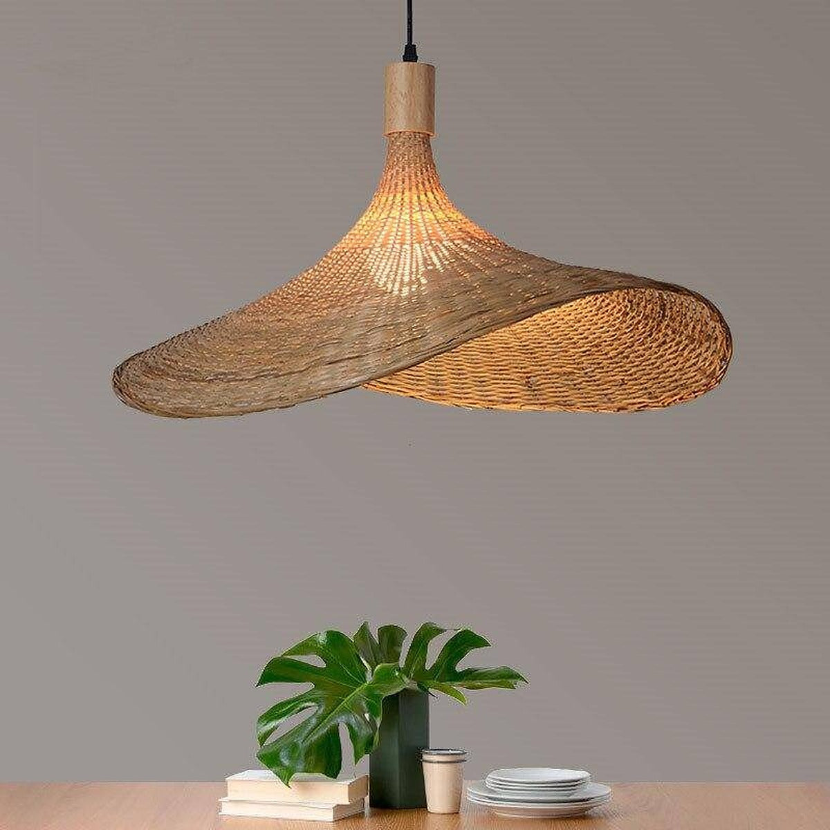 Kasa bamboo hat pendant light lit above a table