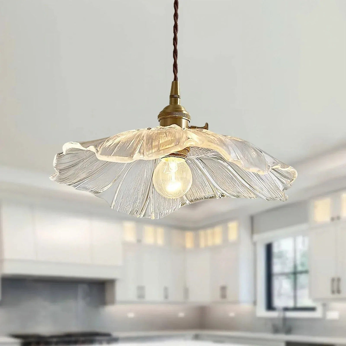 Clear flower glass pendant light glowing in a white kitchen