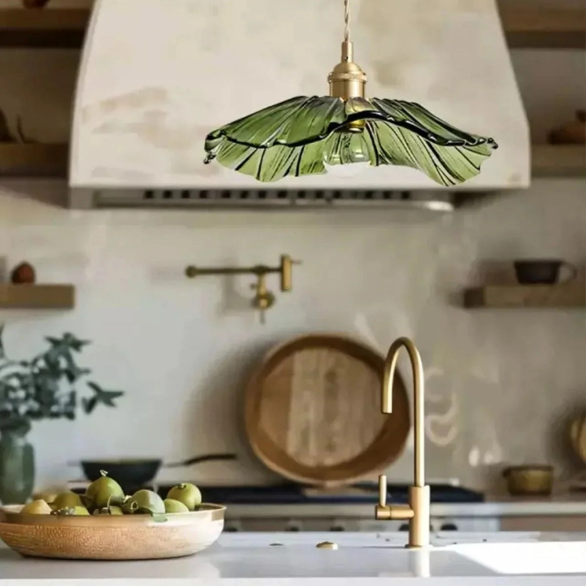 Green flower glass pendant light above a kitchen island with brass tap
