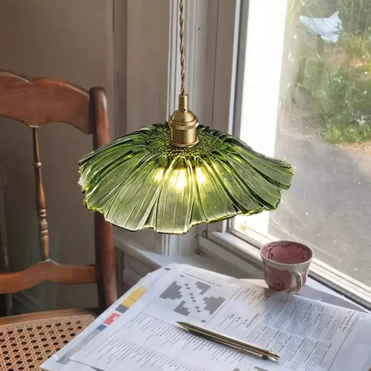 Green flower glass pendant light over a reading table by a window